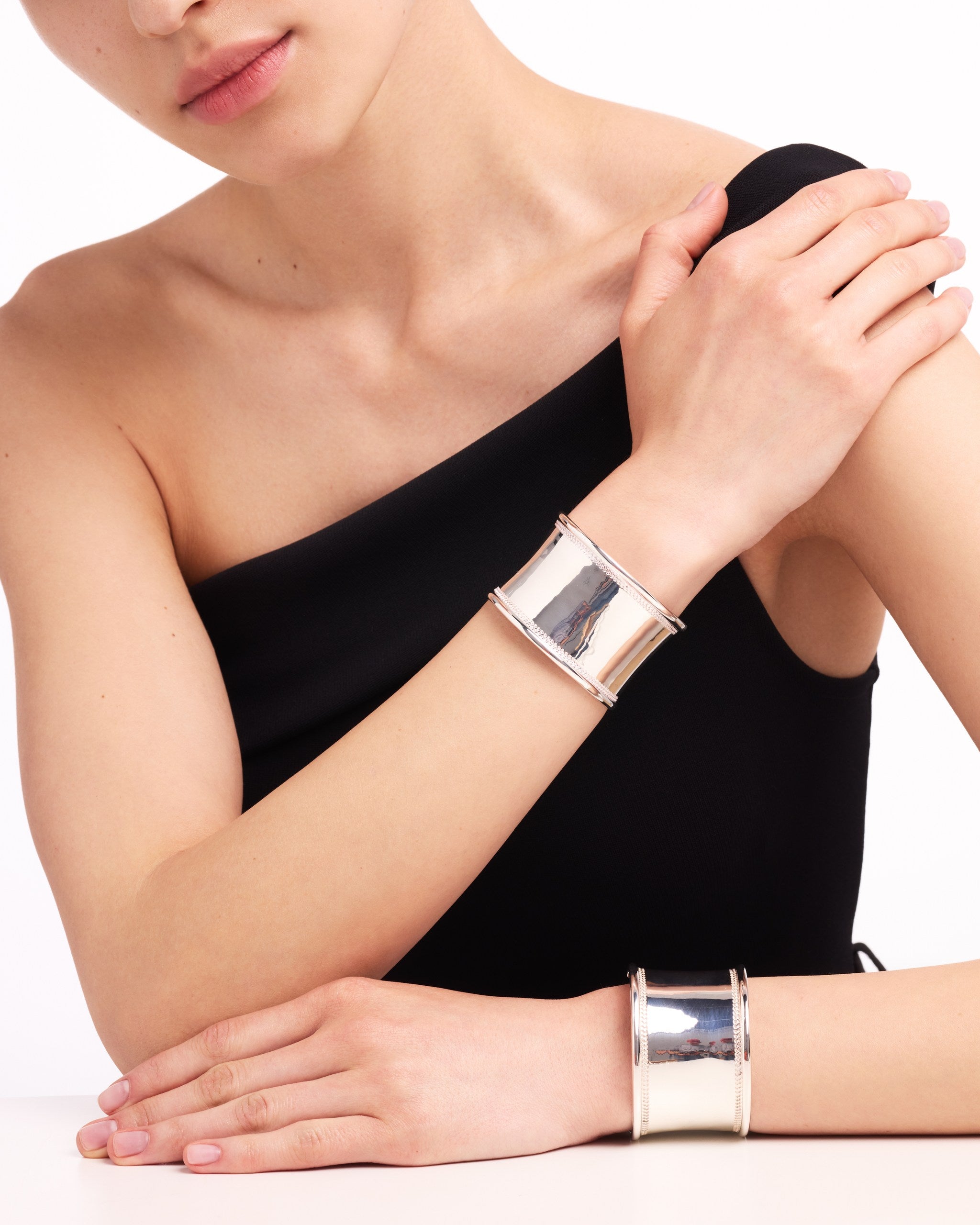 Woman wearing silver bangles on a white background