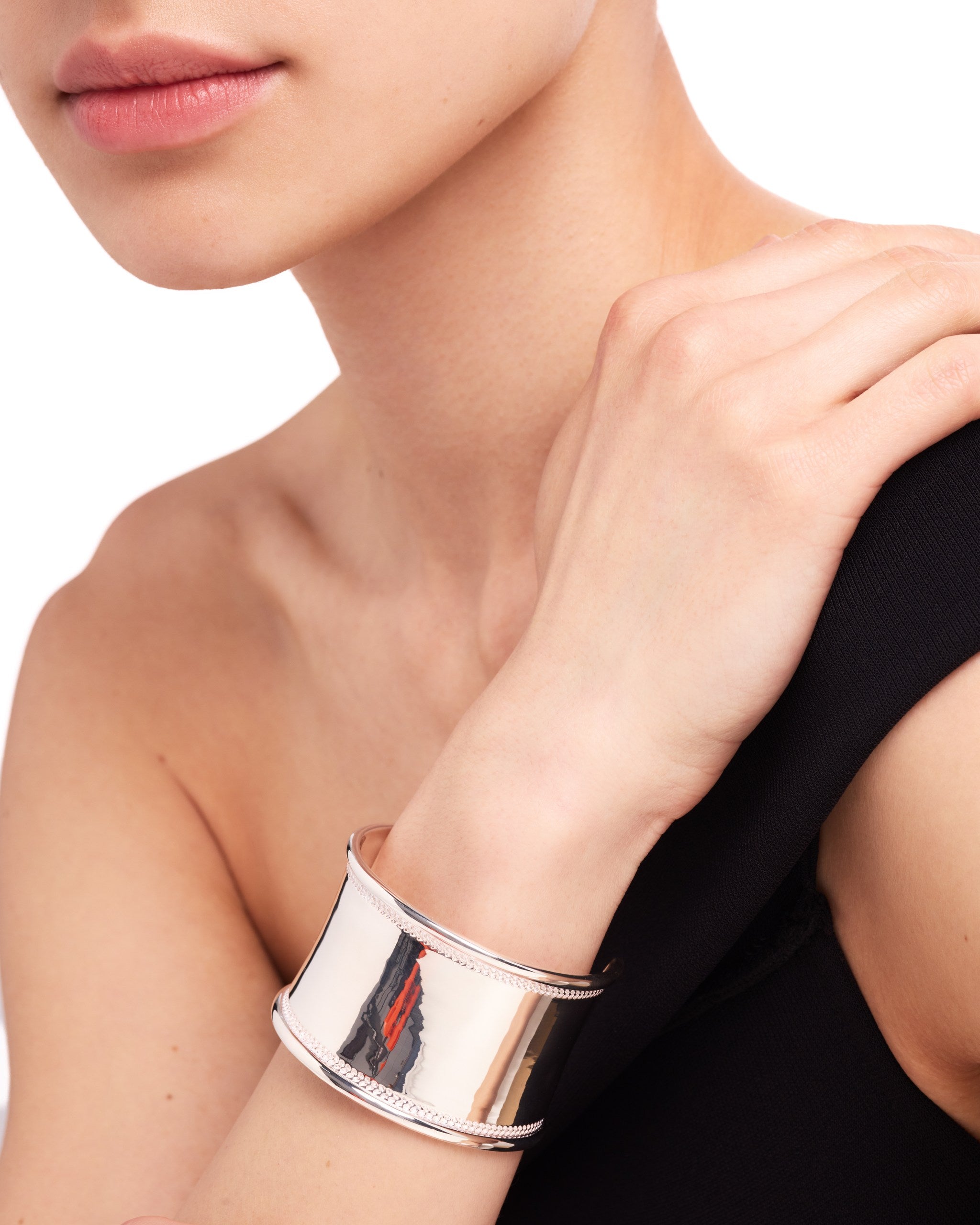 Silver bracelet on a person's wrist with a neutral background